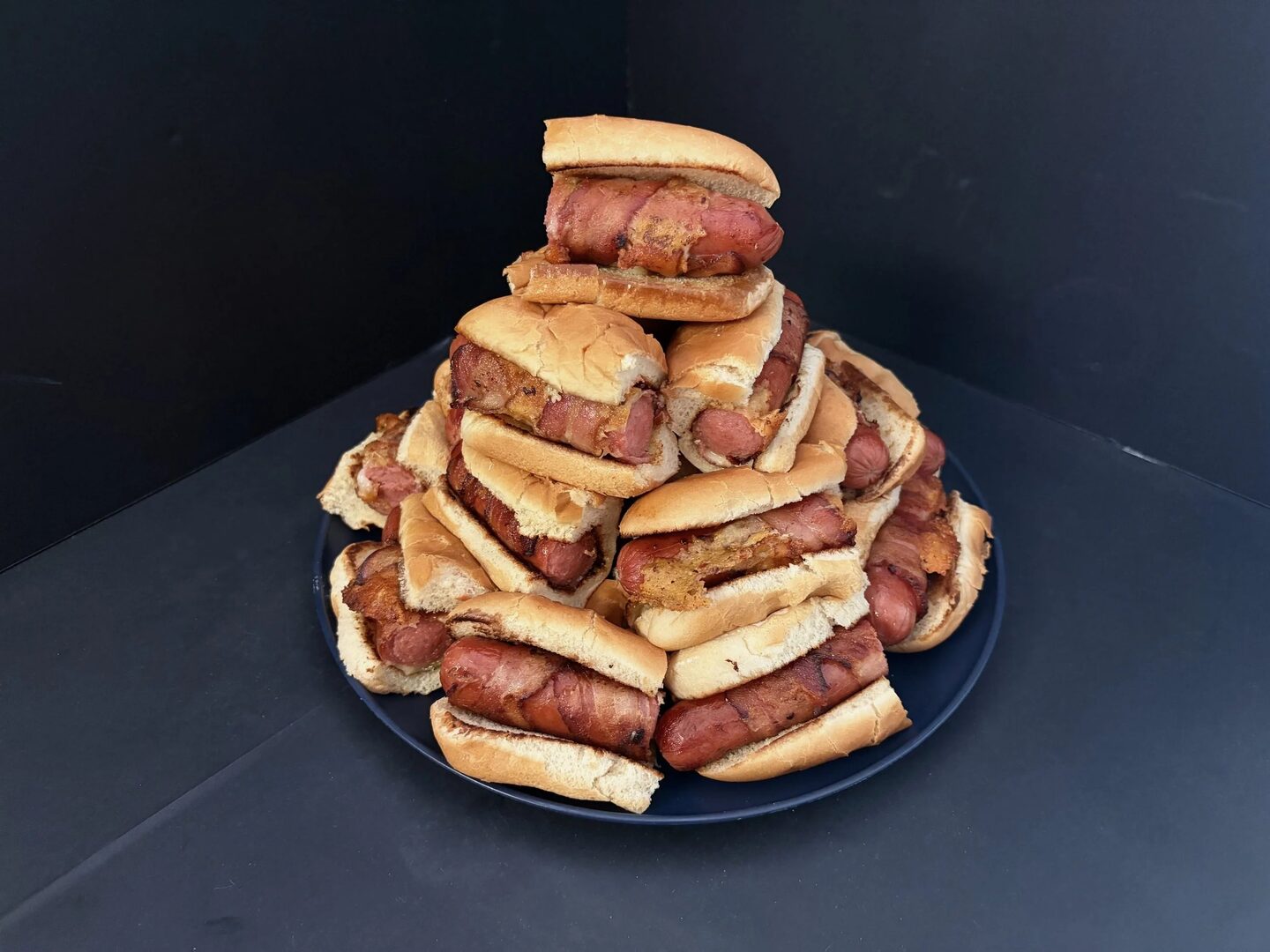 A platter of Dawg Juniors, bacon-wrapped hot dog halves served in small rolls.