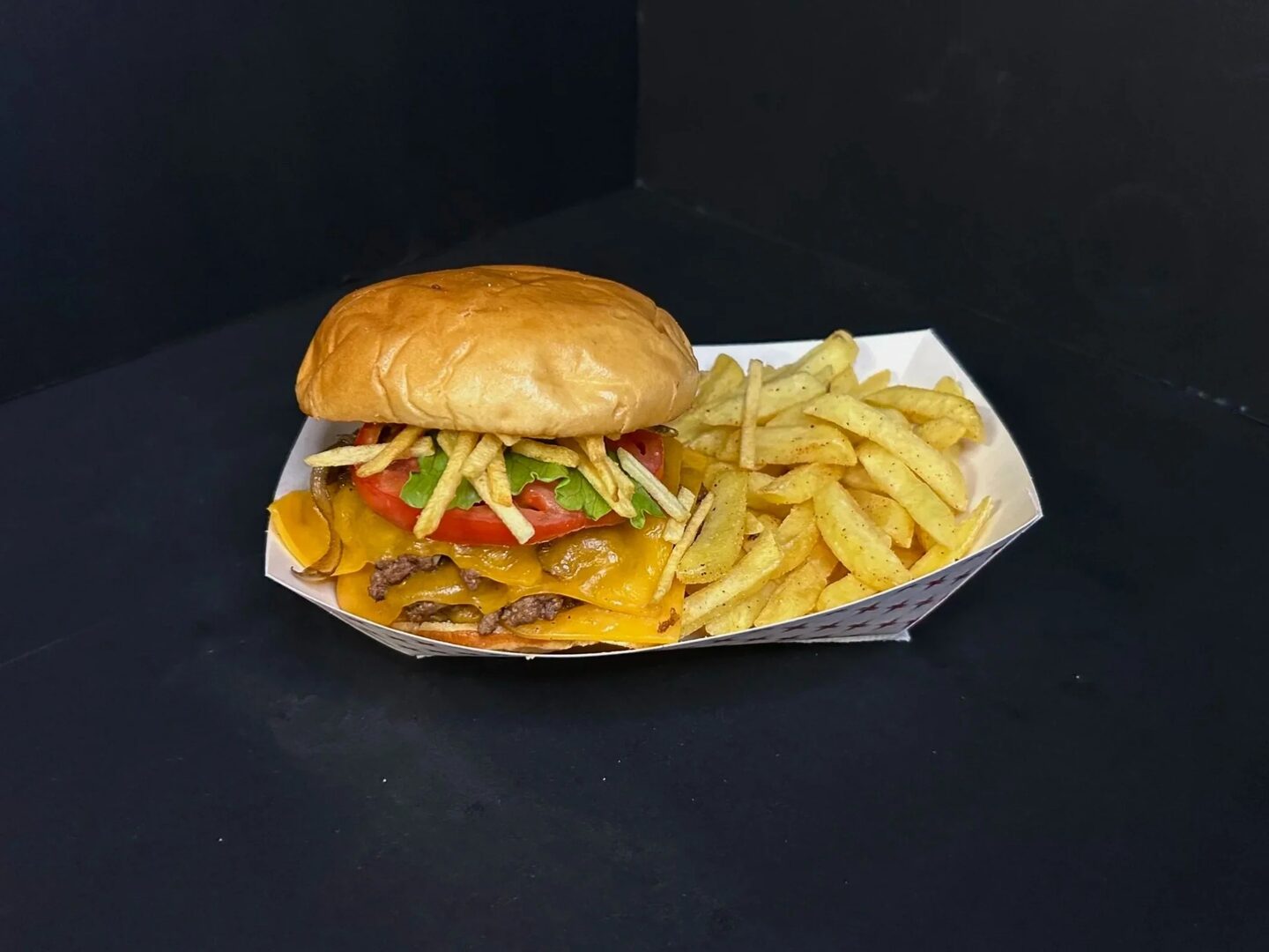 A stacked smash cheeseburger with lettuce and tomato, served with seasoned fries.